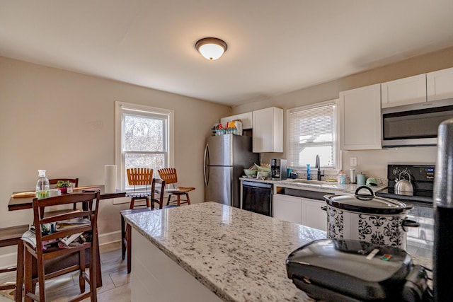 kitchen featuring light stone countertops, stainless steel appliances, light tile patterned floors, white cabinets, and sink