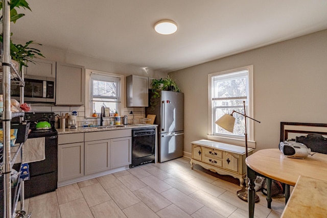 kitchen featuring black appliances, gray cabinetry, a wealth of natural light, and sink