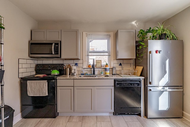 kitchen featuring backsplash, light stone countertops, black appliances, and sink