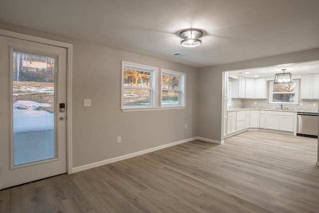 kitchen with sink, white cabinets, dishwasher, light wood-type flooring, and hanging light fixtures