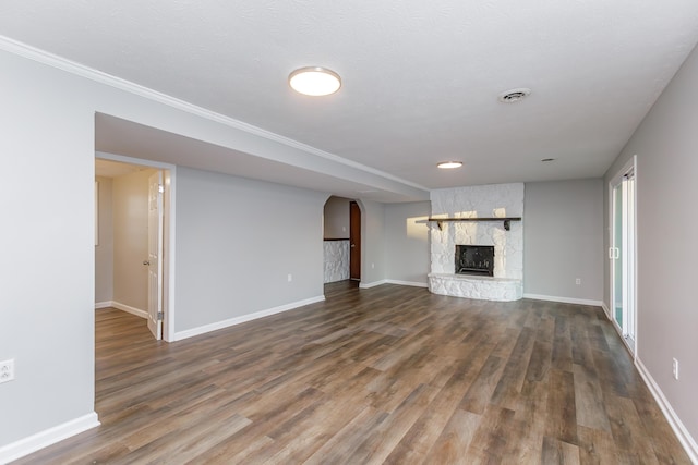 unfurnished living room with dark wood-type flooring and a stone fireplace