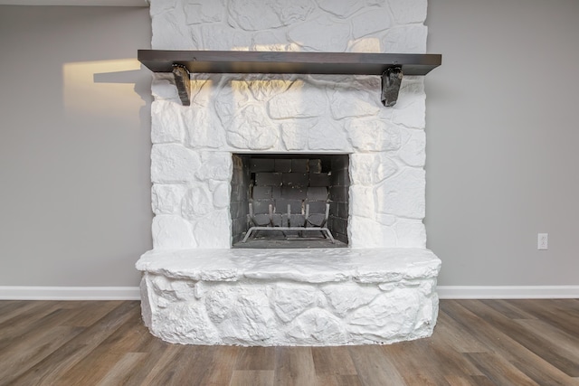 interior details featuring wood-type flooring and a stone fireplace