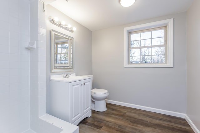 bathroom featuring wood-type flooring, toilet, vanity, and a wealth of natural light