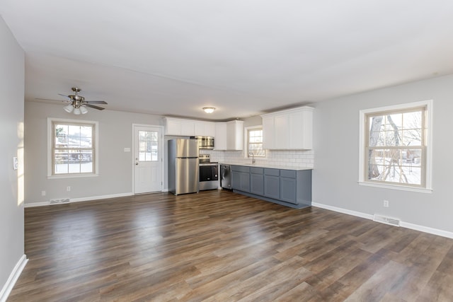 unfurnished living room with ceiling fan, dark wood-type flooring, and sink