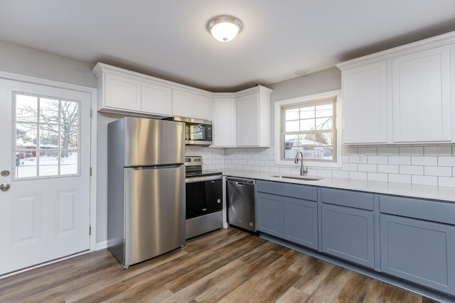 kitchen with stainless steel appliances, white cabinetry, tasteful backsplash, and sink