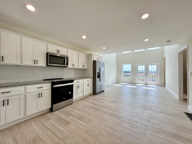 kitchen featuring stainless steel appliances, decorative backsplash, white cabinetry, and light hardwood / wood-style flooring