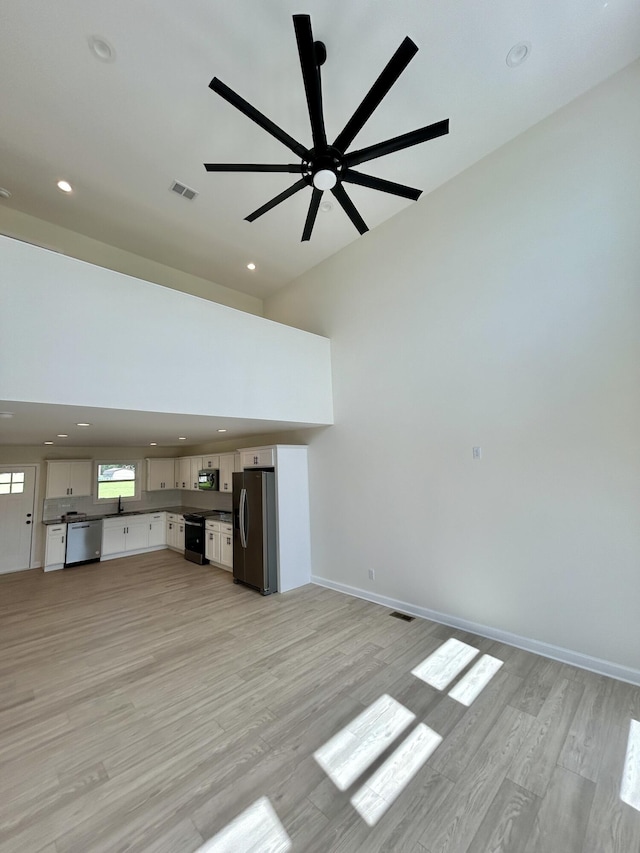 unfurnished living room featuring light wood-type flooring and ceiling fan