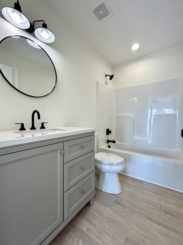 full bathroom with hardwood / wood-style floors, bathtub / shower combination, vanity, and toilet