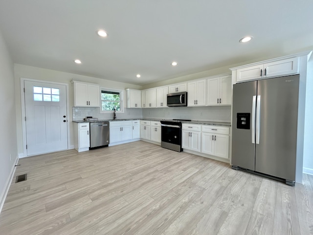 kitchen featuring sink, appliances with stainless steel finishes, decorative backsplash, and white cabinetry