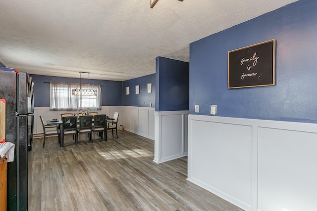 dining area with hardwood / wood-style flooring, a textured ceiling, and a chandelier