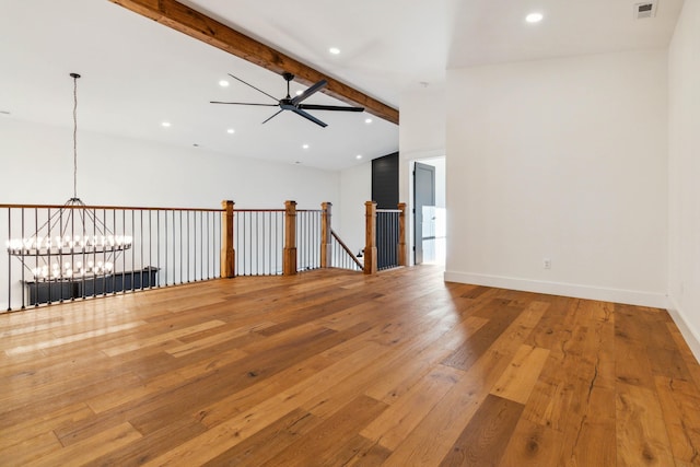 unfurnished room with ceiling fan with notable chandelier, wood-type flooring, and vaulted ceiling with beams