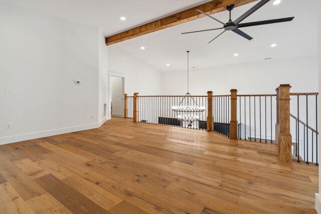 spare room with ceiling fan with notable chandelier, lofted ceiling with beams, and light wood-type flooring