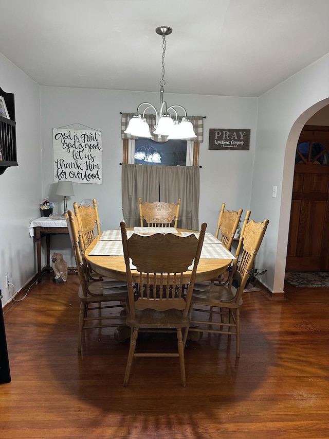 dining area featuring dark wood-type flooring and a notable chandelier