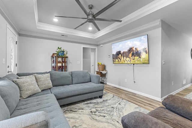 living room featuring hardwood / wood-style flooring, a raised ceiling, ornamental molding, and ceiling fan