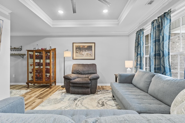 living room with a raised ceiling, crown molding, and wood-type flooring