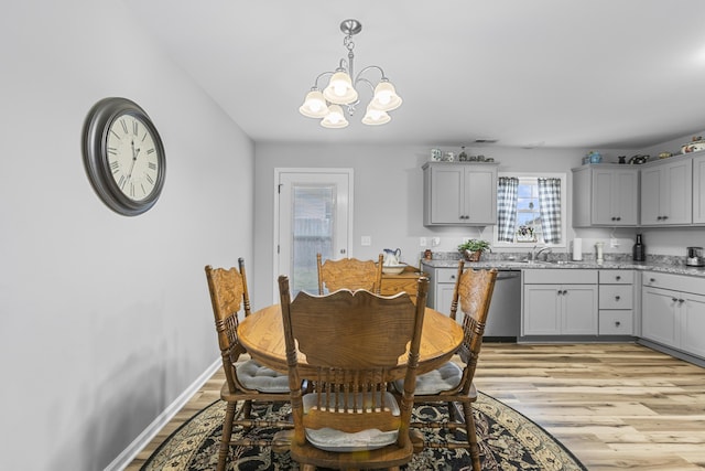 dining room featuring sink, an inviting chandelier, and light hardwood / wood-style flooring