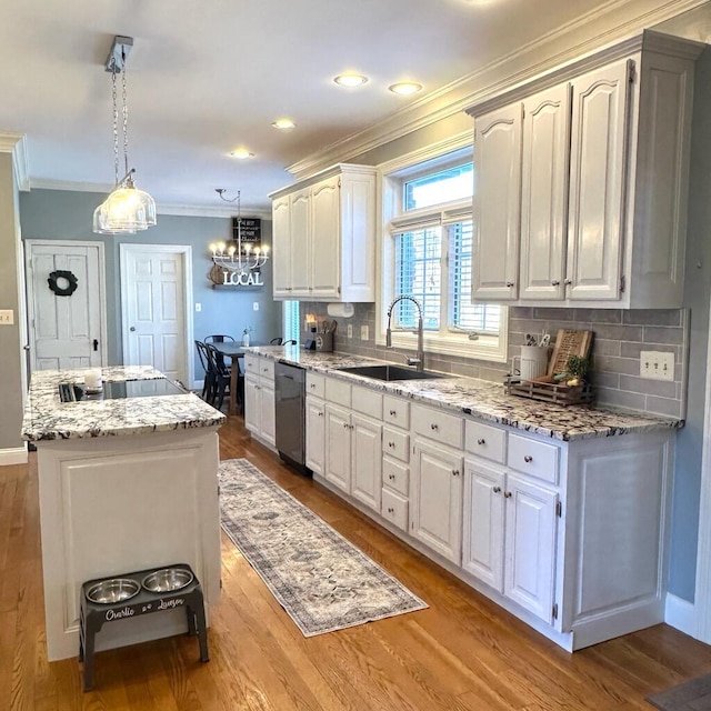 kitchen featuring white cabinetry, pendant lighting, stainless steel dishwasher, and sink