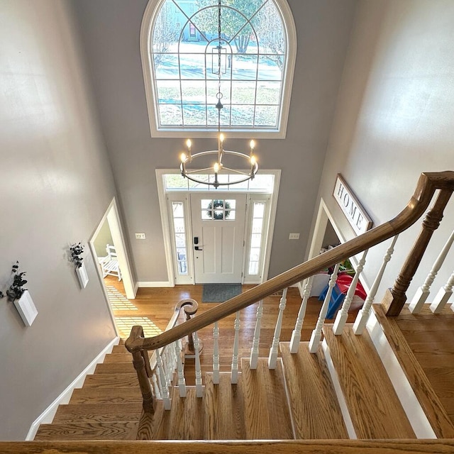 foyer entrance with a towering ceiling, hardwood / wood-style floors, and a notable chandelier