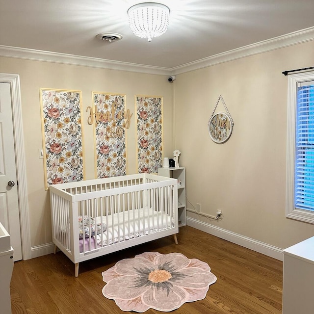 bedroom featuring hardwood / wood-style floors, a nursery area, and crown molding