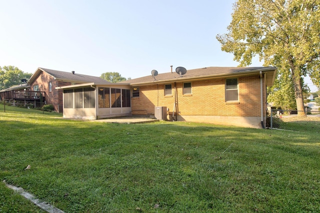 rear view of property featuring a patio, a sunroom, and a lawn