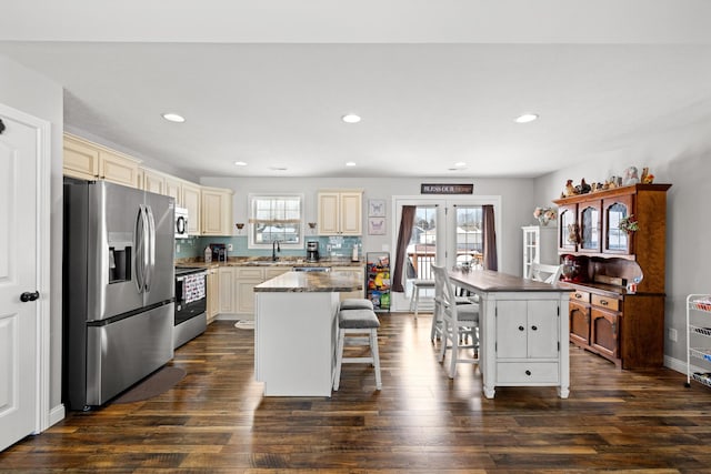 kitchen featuring a breakfast bar, appliances with stainless steel finishes, a center island, and plenty of natural light