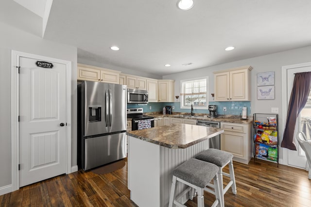 kitchen featuring cream cabinetry, appliances with stainless steel finishes, a breakfast bar area, and a kitchen island