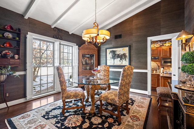 dining space featuring dark hardwood / wood-style flooring, an inviting chandelier, and vaulted ceiling with beams