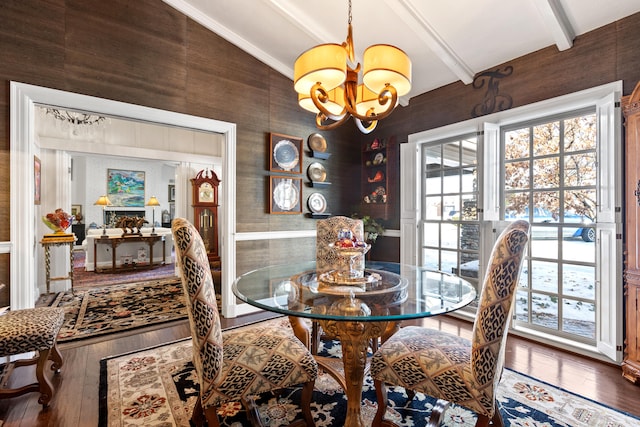 dining room with wooden walls, vaulted ceiling with beams, a chandelier, and hardwood / wood-style flooring