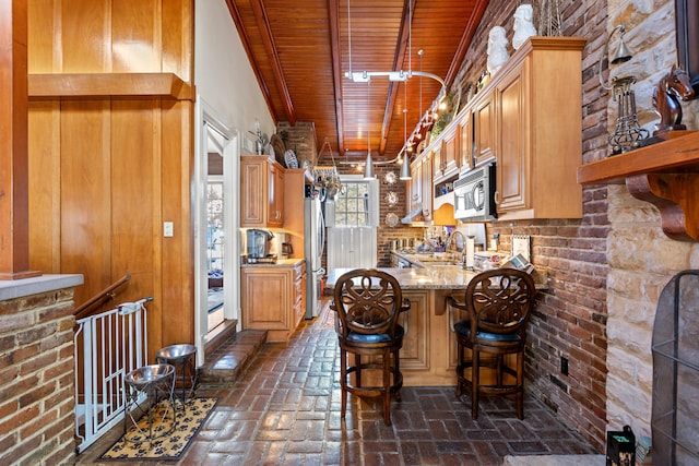 kitchen with stainless steel appliances, sink, light stone counters, a kitchen breakfast bar, and kitchen peninsula