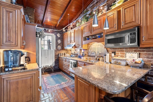 kitchen featuring stainless steel appliances, sink, stone counters, a kitchen breakfast bar, and hanging light fixtures