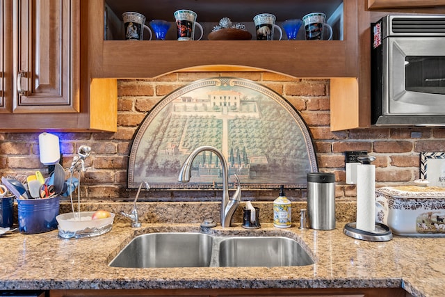 kitchen featuring light stone counters, tasteful backsplash, and sink