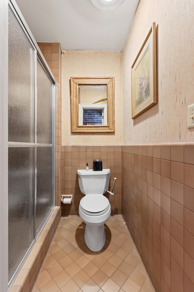 bathroom with tile walls, tile patterned flooring, an enclosed shower, and toilet