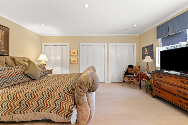 bedroom with multiple closets, ornamental molding, and light hardwood / wood-style floors