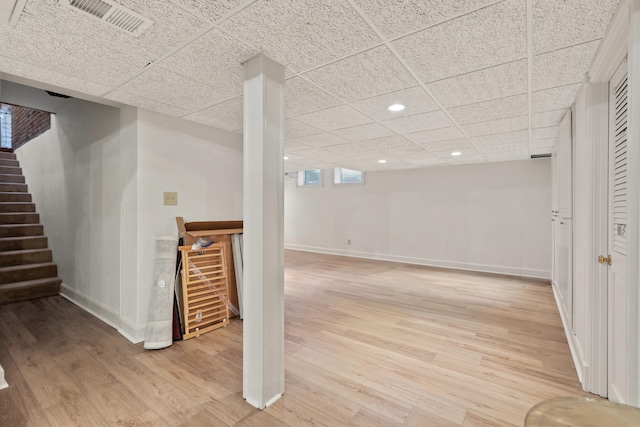 basement featuring light hardwood / wood-style floors and a paneled ceiling