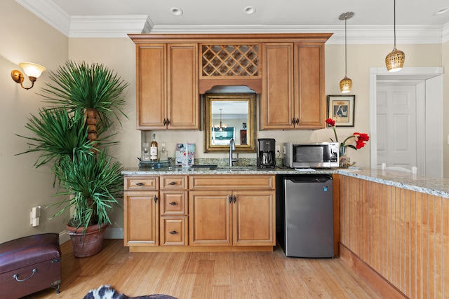 kitchen featuring stainless steel appliances, light stone countertops, ornamental molding, sink, and decorative light fixtures