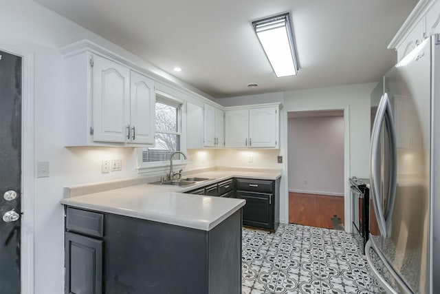 kitchen featuring sink, light tile patterned floors, white cabinetry, and stainless steel refrigerator