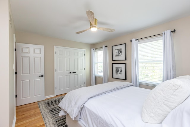 bedroom with ceiling fan, light hardwood / wood-style floors, multiple windows, and a closet