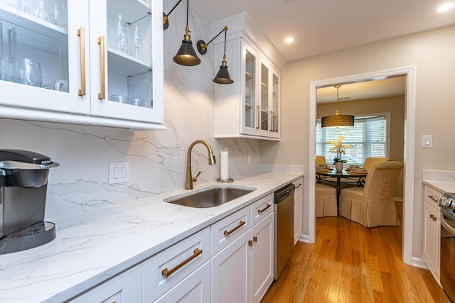 kitchen with decorative backsplash, sink, white cabinetry, light hardwood / wood-style flooring, and stainless steel appliances