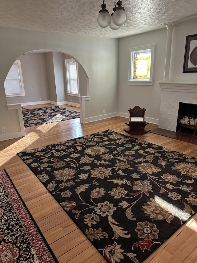 living room with a brick fireplace, hardwood / wood-style floors, a textured ceiling, and a wealth of natural light