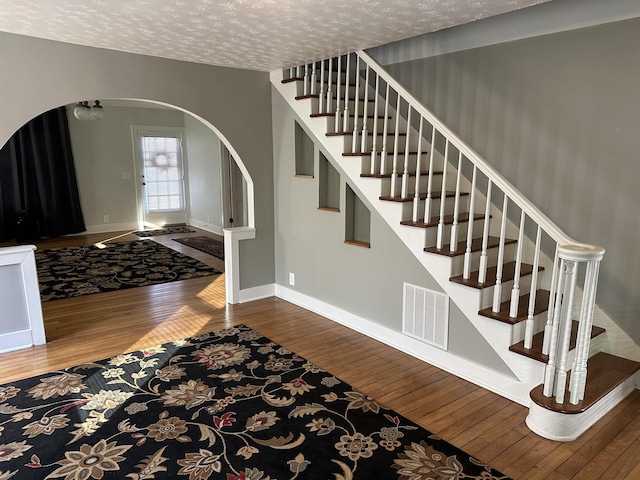 staircase with wood-type flooring and a textured ceiling