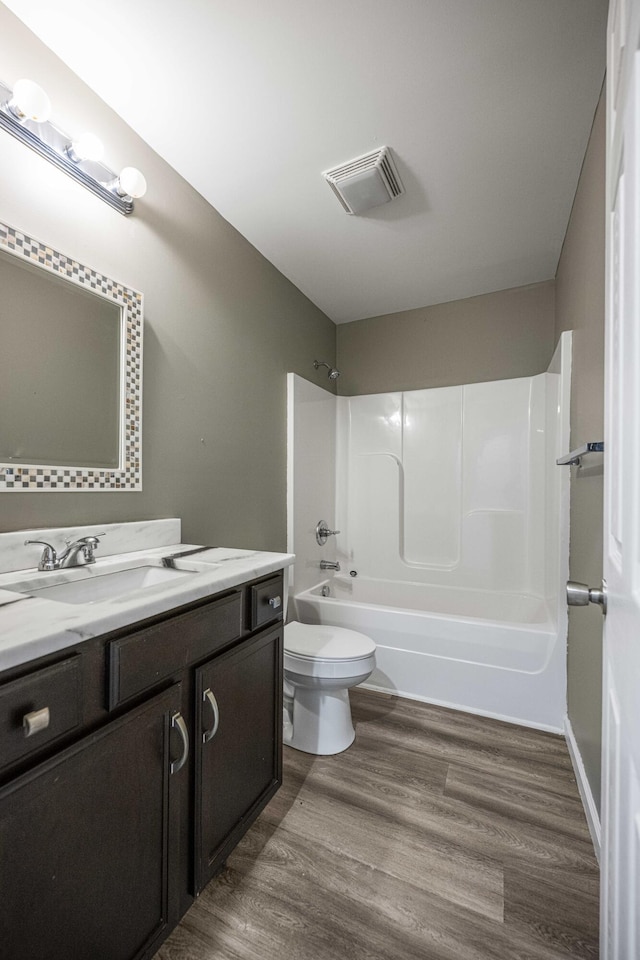 full bathroom with bathing tub / shower combination, wood-type flooring, vanity, and toilet