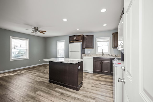 kitchen featuring sink, dark brown cabinets, plenty of natural light, a kitchen island, and white appliances