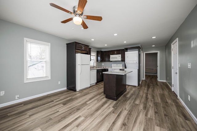 kitchen with sink, dark hardwood / wood-style flooring, a center island, dark brown cabinetry, and white appliances