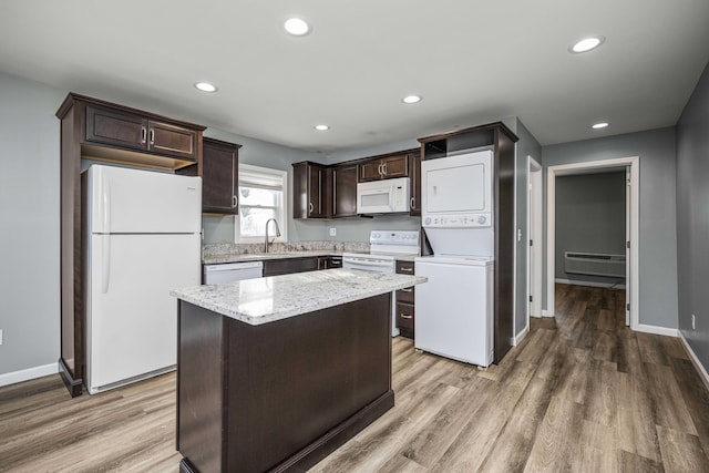 kitchen featuring white appliances, a wall mounted AC, stacked washer / dryer, wood-type flooring, and a kitchen island