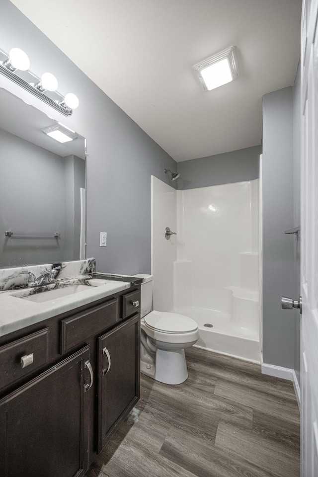 bathroom featuring vanity, hardwood / wood-style floors, toilet, and walk in shower