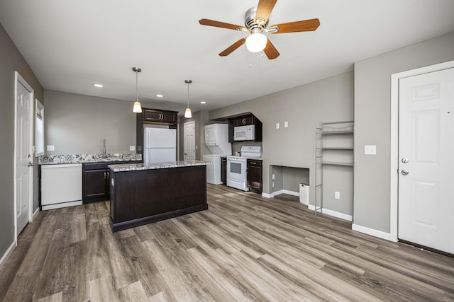 kitchen with dark brown cabinetry, white appliances, a center island, and hardwood / wood-style flooring