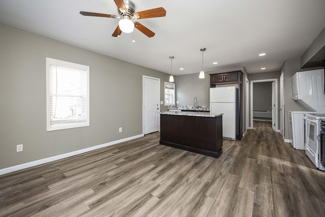 kitchen with pendant lighting, a center island, dark wood-type flooring, dark brown cabinets, and white appliances