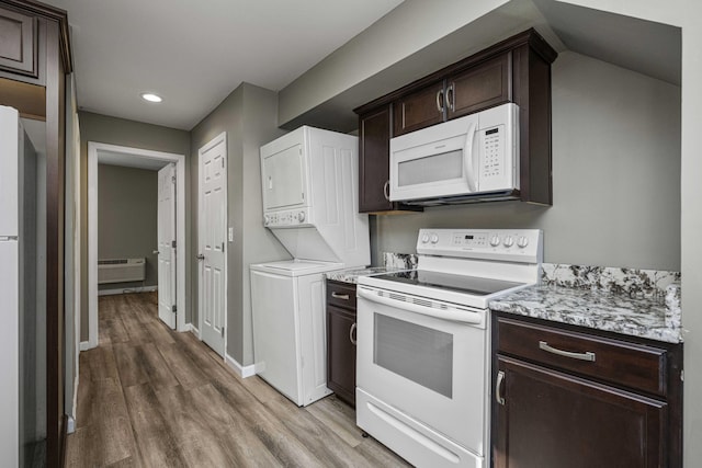 kitchen with stacked washer / drying machine, white appliances, wood-type flooring, and dark brown cabinets