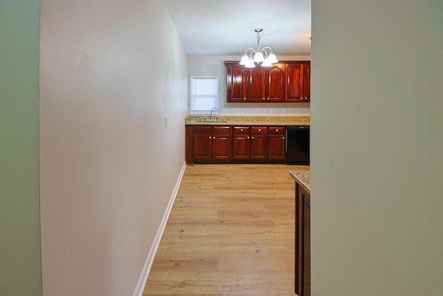 kitchen featuring light hardwood / wood-style floors, hanging light fixtures, a notable chandelier, sink, and black dishwasher