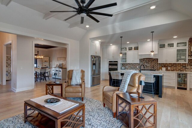 living area featuring vaulted ceiling, beverage cooler, light wood-type flooring, and ceiling fan